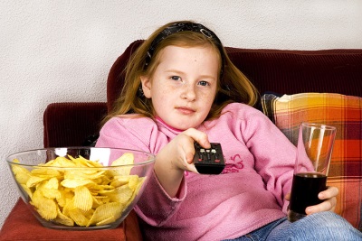 Girl in front of the TV with cola and chips