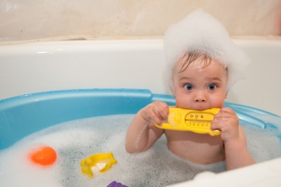 The boy bathes in a bath with a thermometer for water