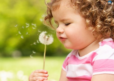 Girl blowing on dandelion