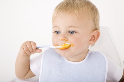 The baby eats with a spoon at 11 months