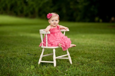 A 9 month old baby is sitting on a chair