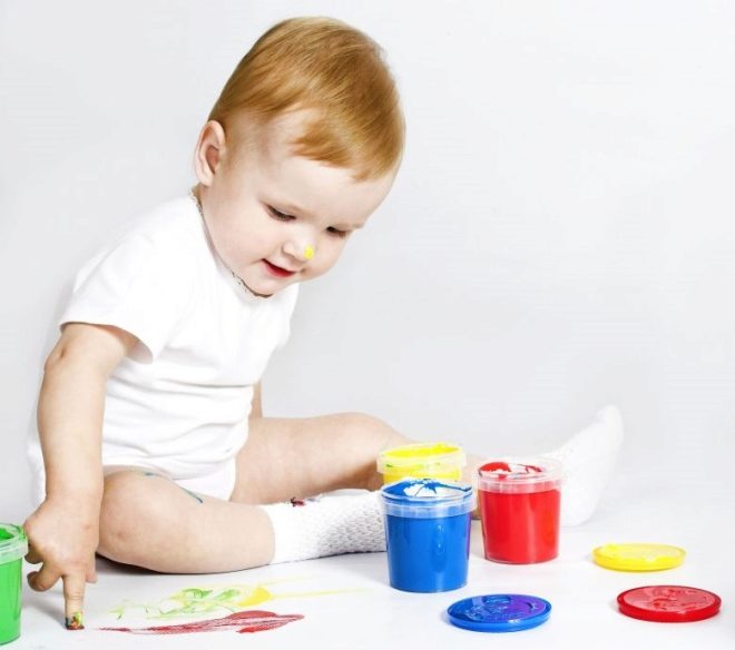 A child in 1 year draws with finger paints